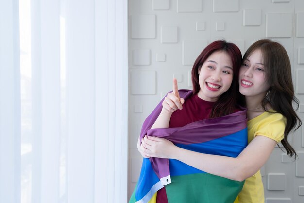 Photo lgbt couples cover rainbow flags around their loved ones to keep warm and gaze out their hotel room windows together