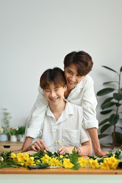 LGBT-liefdesmomenten en levensstijlconcept Aanhankelijk mannelijk homopaar dat samen tijd doorbrengt en geniet van het regelen van bloemen in een gezellig huis