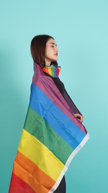 LGBT-meisje en trotsvlag. sexy lesbisch meisje en lgbt-vlag staan. blauw groene achtergrond.