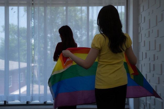 LGBT-paren bedekken regenboogvlaggen rond hun geliefden om warm te blijven en samen uit de ramen van hun hotelkamer te staren