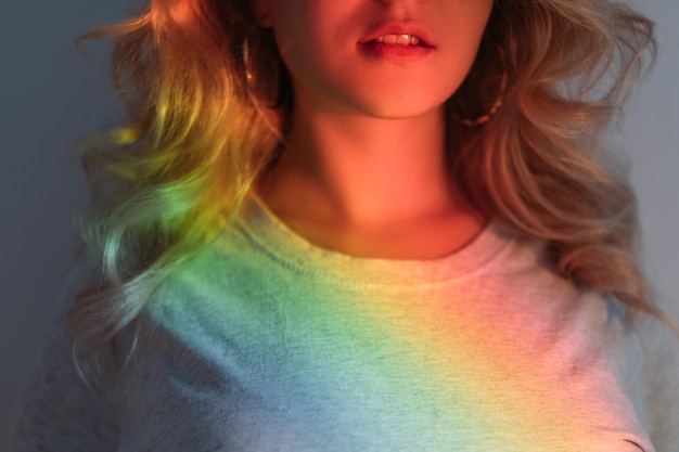 LGBT pride. Gay rights. Diversity freedom. Peace harmony. Blonde lesbian woman in blur rainbow glow. Blue red green yellow color gradient neon lights on dark background.