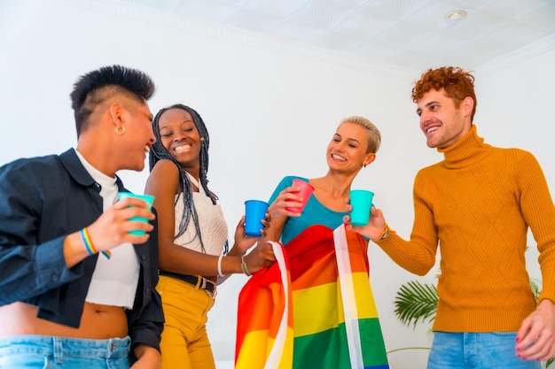 LGBT pride lgbt rainbow flag group of friends dancing and toasting with glasses in a house at party