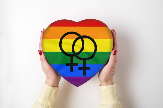 LGBT rainbow lesbian community flag on a heart shape box in female hands. Pride symbol. Top view