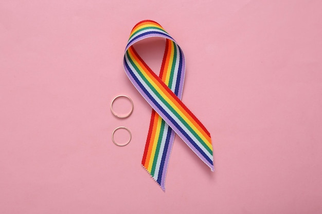 LGBT regenboog lint trots tape symbool met gouden trouwringen op roze achtergrond