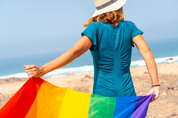 Lgbt-symbool, een onherkenbare lesbische persoon van achteren die met de vlag zwaait bij de zee