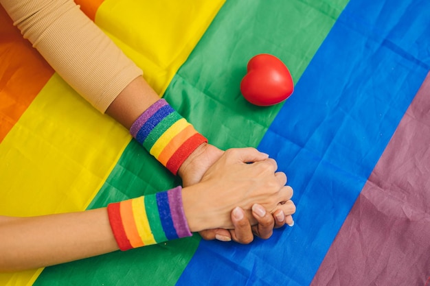 LGBT Transgender woman hand hold support together on rainbow flag with love heart for sexuality rights campaign people background