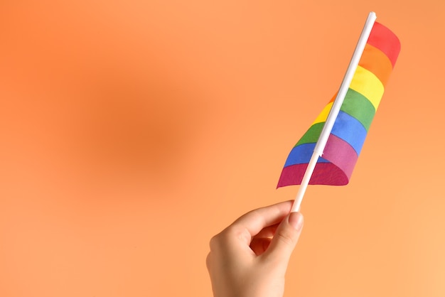 Lgbt-vlag in vrouwenhand op oranje achtergrond. ruimte kopiëren.