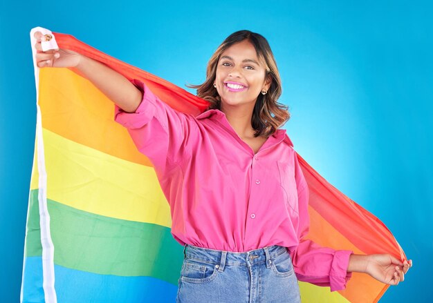 Foto ritratto di bandiera lgbtq e donna con sostegno orgoglio e felicità su uno sfondo blu dello studio persona femminile alleata o modello con simbolo per l'uguaglianza della comunità queer o i diritti transgender con libertà