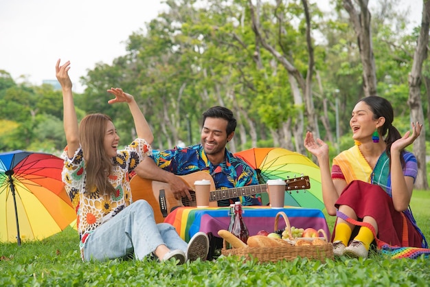 Foto gruppo lgbtq seduto cantando e mangiando nel parco e scattando foto felicemente concetto di stile di vita lgbtq