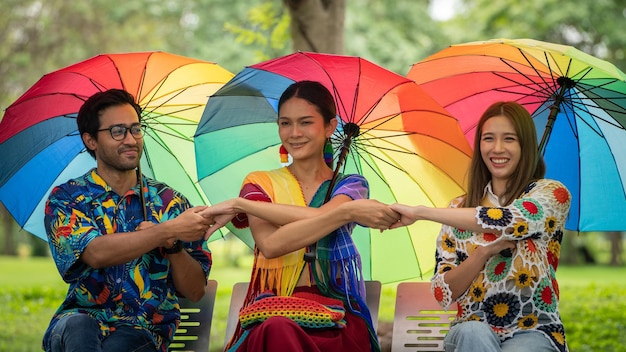 LGBTQLGBTゲイのお祝いのコンセプトの肖像画公園のシンボルでレインボー傘を保持しているゲイの友人