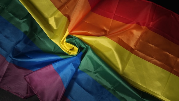 Photo lgbtq pride flag. lesbian gay bi sexsual transgender queer. homosexsual pride rainbow flag in gay hand. black background. represent symbol of freedom, peace, equality and love. lgbtq concept.