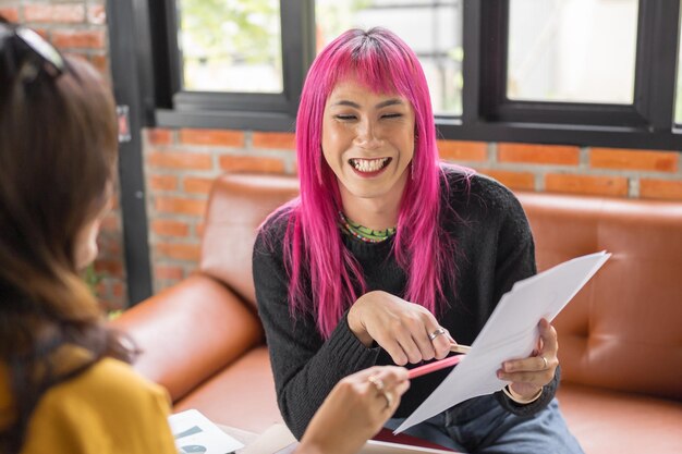 LGBTQ transgender man Mooie Authentieke Specialist met roze haar en niet-binary trans werken samen Werken Design in creatieve werkplek teamwerk collega's Gendergelijkheid