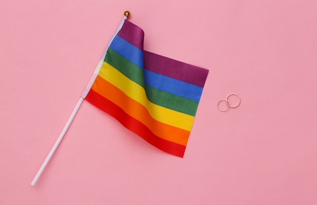 LHBT-huwelijk. LGBT-regenboogvlag en gouden ringen op roze achtergrond. Tolerantie, vrijheid