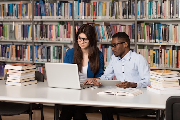 In The Library  Handsome Two College Students With Laptop And Books Working In A High School  University Library  Shallow Depth Of Field