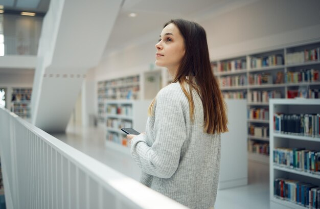 Photo library thinking student and woman with phone in university college or school ideas scholarship and female with mobile smartphone for knowledge researching or studying learning and education