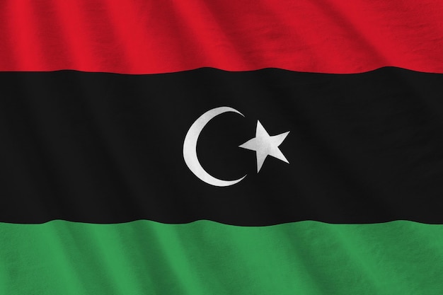 Libya flag with big folds waving close up under the studio light indoors The official symbols and colors in banner