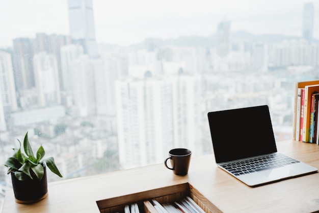 Licht appartement interieur met minimalistische werkplek en transparante stoel en tafel met laptop en boeken op een witmarmeren betonnen vloer bij raam met uitzicht op de stad