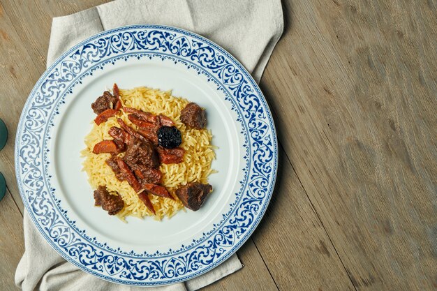 Licht, dieet pilau met rundvlees en wortelen op een witte plaat op een houten oppervlak. Bovenaanzicht met kopie ruimte voor tekst. Traditionele oosterse keuken