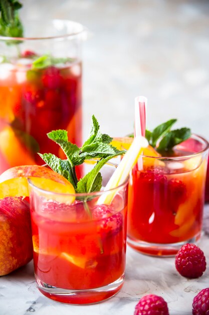 Licht zomer verfrissend drankje met fruit en bessen - sangria. in glazen op een grijze tafel