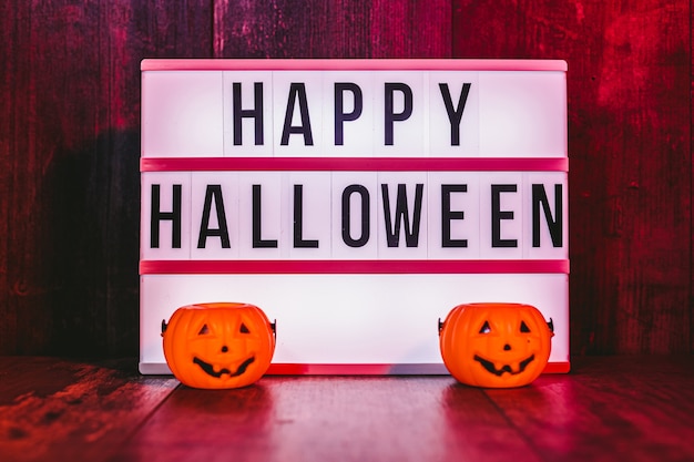 Lichtbakje met 'Happy Halloween' bericht en kleine pompoenen met rode sfeer