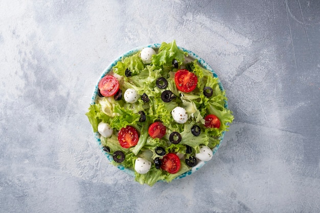 Lichte dieetsalade met sla, tomaten, olijven en mozarellakaas. Bovenaanzicht