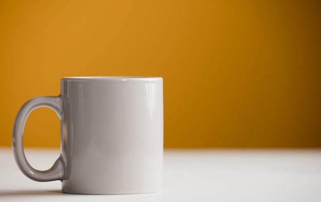 Lichtgrijze kop koffie op tafel met gele achtergrond