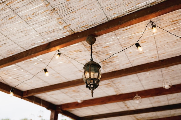 Lichtmetalen kroonluchter onder het plafond gemaakt van bamboe en guirlande