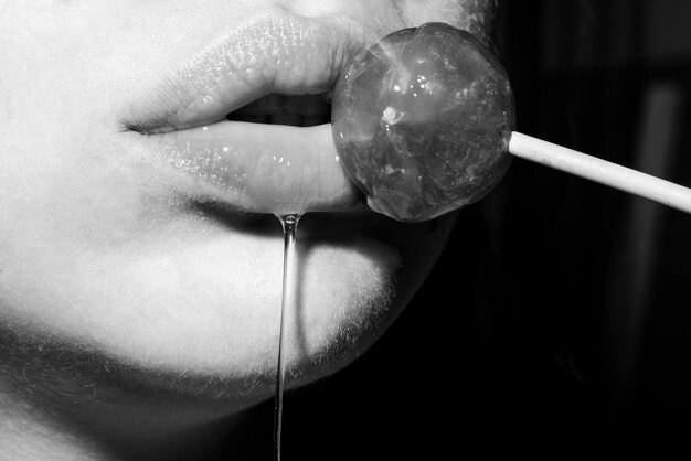 Premium Photo Licking candy lollipop model woman lips sucking a candy oral sex blow job concept glamor sensual model with red lips eat sweats lolly image pic