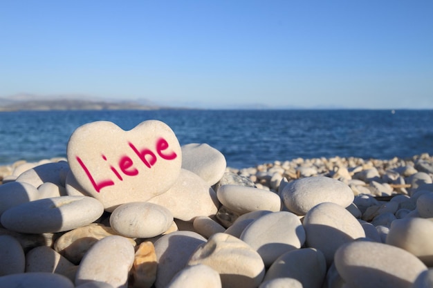 Liebe geschreven op hartvormige steen op het strand