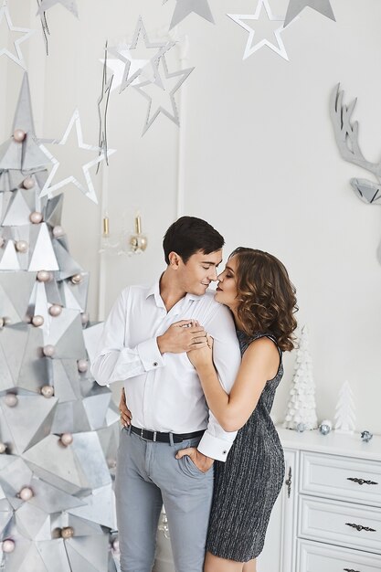 Lief jong heteroseksueel paar verliefd poseren in woonkamer interieur ingericht voor kerstvakantie