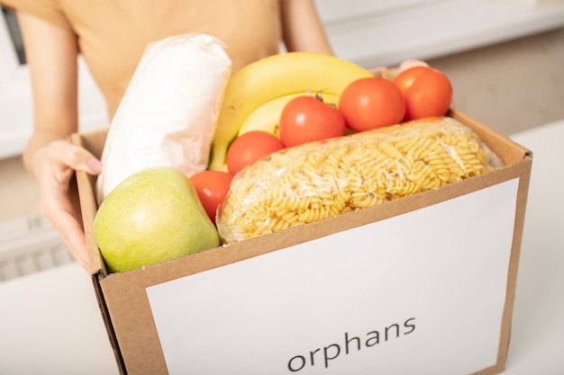 Foto liefdadigheid en hulp aan mensen in nood vrouwenhanden houden een doos voedselproducten voor weeskinderen vast