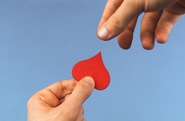 Liefdadigheidsconcept helpende hand voor werelddonordag jonge jongen geeft een rood hart in de vorm van een druppeldonatiefoto