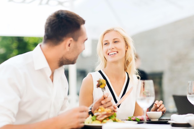 Foto liefde, datum, mensen, vakantie en relatiesconcept - gelukkig paar dat salade eet voor diner bij café of restaurantterras