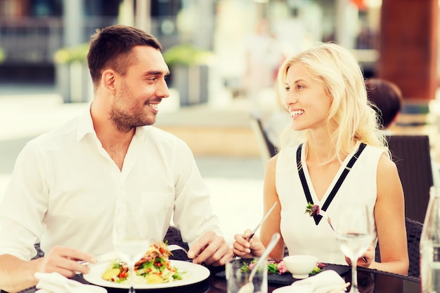 liefde, datum, mensen, vakantie en relatiesconcept - gelukkig paar dat salade eet voor diner bij café of restaurantterras