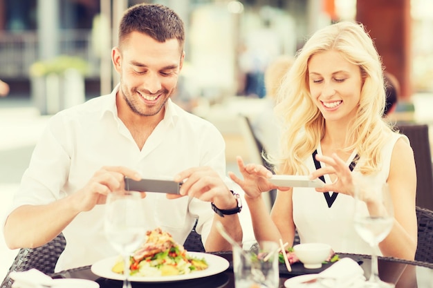 Foto liefde, datum, technologie, mensen en relaties concept - gelukkig stel met smatphone die foto's maakt van eten in restaurant