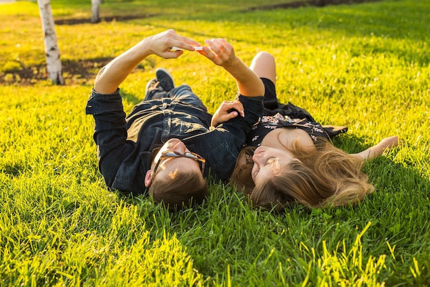 Liefde en mensen concept - gelukkig tienerpaar liggend op het gras en selfie nemen op smartphone in de zomer.