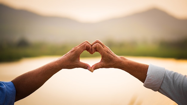 Liefde en Valentijnsdag concept. Een gelukkig hoger paar dat hartteken toont