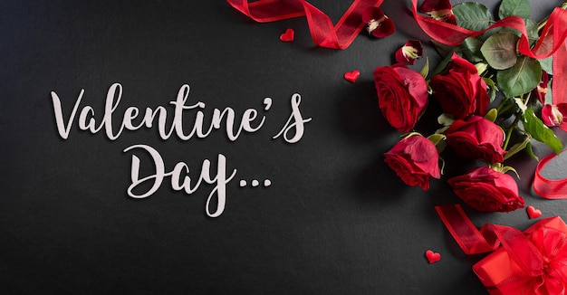 Liefde en Valentijnsdag concept gemaakt van rode roos en geschenkdoos op zwarte houten achtergrond met de tekst.