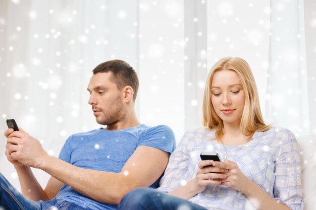 liefde, familie, technologie, internet en mensenconcept - koppel thuis met smartphones