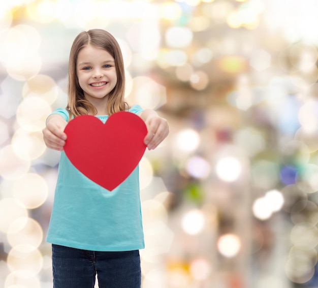 Foto liefde, geluk en mensenconcept - glimlachend meisje dat rood hart geeft