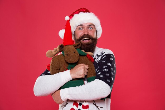 Liefde gever meer dan cadeau. Bebaarde man knuffel speelgoed met liefde. Gelukkige hipster viert nieuwjaar en Kerstmis. Ik hou van Kerstmis. Kerst gaat over liefde.