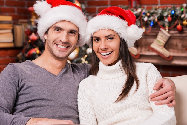 Liefde is het beste cadeau. Mooie jonge verliefde paar bonden aan elkaar en lachend met kerstboom op de achtergrond