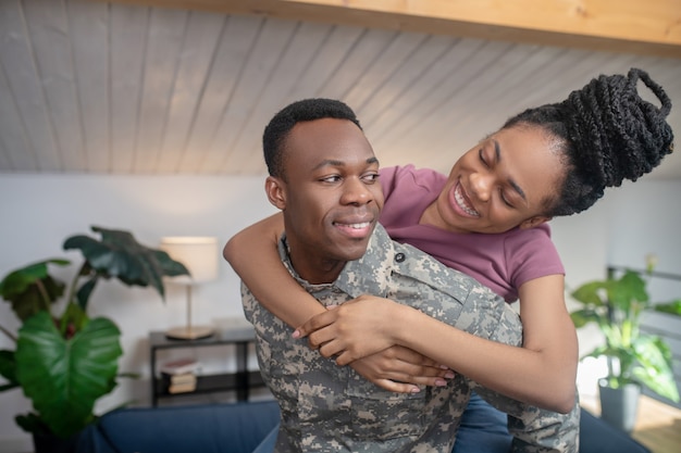 Liefde. Jonge, donkere, sterke militaire man en mooie vrouw in een vrolijke bui die elkaar thuis met liefde aankijken