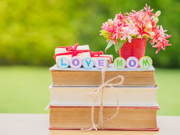 LIEFDE MOM alfabet op stapel boeken rood hart en bloem op achtergrond.