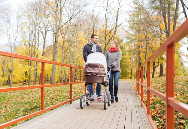 liefde, ouderschap, familie, seizoen en mensenconcept - glimlachend paar met babykinderwagen in herfstpark