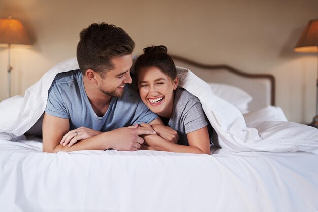 Liefde paar en ontspannen op het bed met lachen knuffelen en gelukkig voor de reis in het hotel luxe accommodatie man en vrouw in de slaapkamer met grap liefde en huwelijksreis naar het resort met veiligheid en ondersteuning