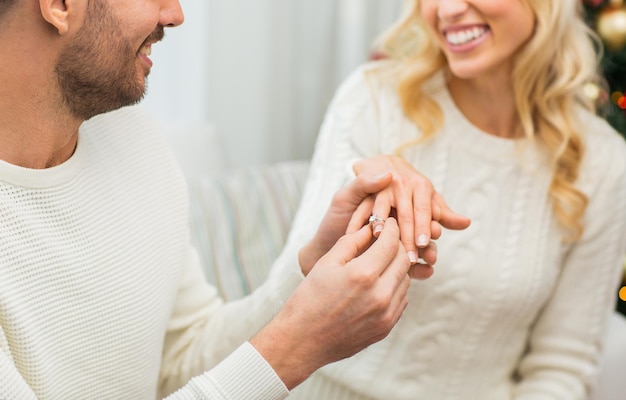 Foto liefde, paar, relatie en vakantie concept - gelukkige man die diamanten ring geeft aan vrouw voor kerstmis