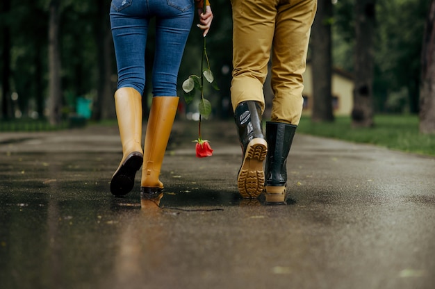 Liefde paar wandelingen in park, regenachtige zomerdag. Man en vrouw vrije tijd samen, romantische date op wandelpad, nat weer in steegje