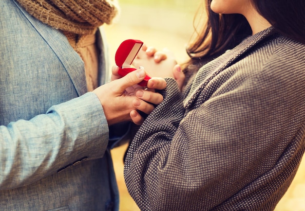 liefde, relatie, familie en mensen concept - close-up van paar met rode geschenkdoos in herfstpark