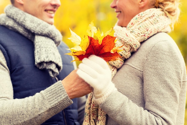 Foto liefde, relatie, familie en mensenconcept - close-up van gelukkig lachend paar met esdoornbladeren in herfstpark